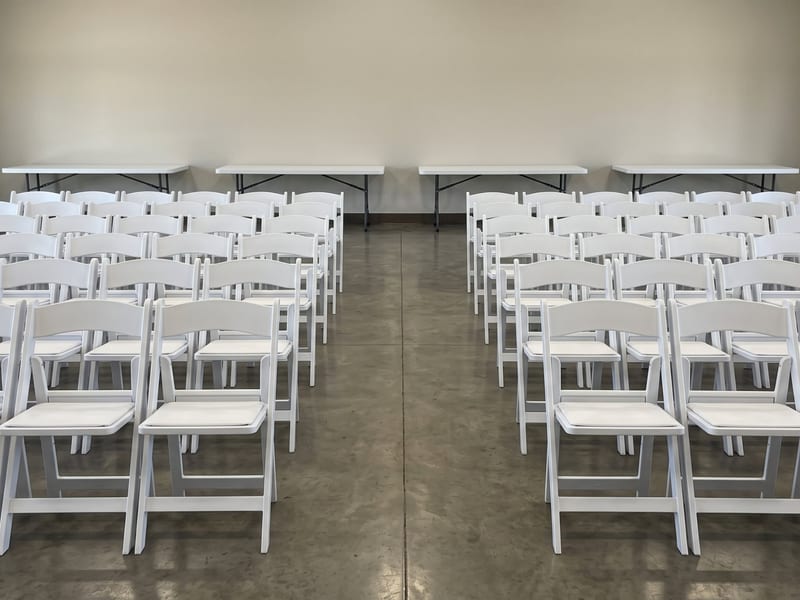 Rows of clean white folding chairs set for an event